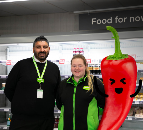 Asda Express colleagues smiling next to chilli pepper with drawn-on smiley face