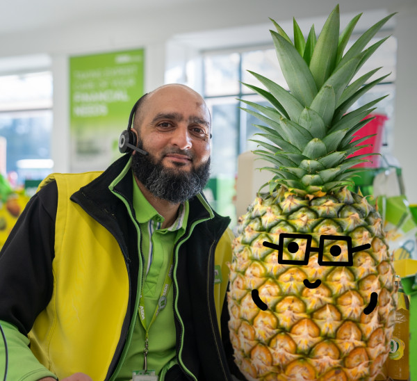 Colleague smiling next to pineapple with drawn-on smiley face